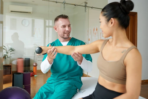 A physical therapist performing car accident physical therapy for a victim by stretching out her arm while she holds a weight.