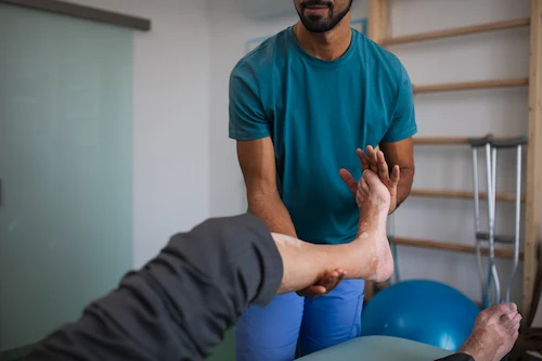 A physical therapist performing car accident physical therapy for a victim by performing leg stretches on them.