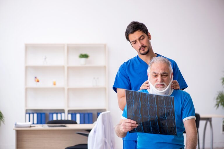Healthcare provider in blue scrubs examining a senior male patient wearing a neck brace while reviewing a spinal X-ray for neck pain treatments.