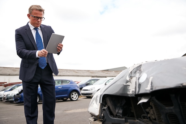 Insurance adjuster inspecting car accident damage after a partial fault collision